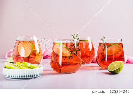 Alcoholic cocktail pink negroni with lime in glasses on table Alcoholic cocktail pink negroni with lime in glasses on table 125294243