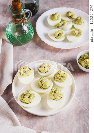 Avocado deviled eggs for appetizer on plate on table vertical view Avocado deviled eggs for appetizer on plate on table vertical view 125294274