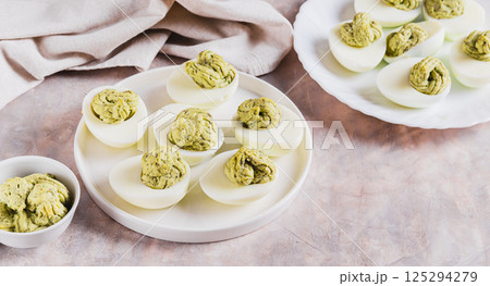 Eggs stuffed with avocado and yolk mixture on a plate on a table web banner 125294279