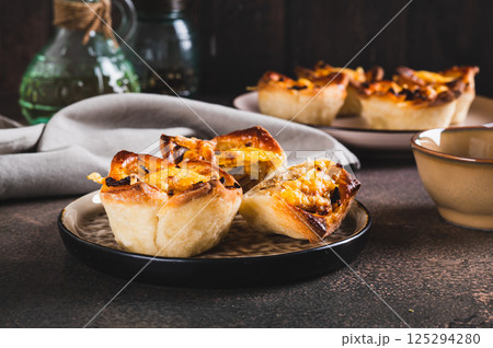 Mini tartlets with caramelized onions and cheese on a plate on a table 125294280