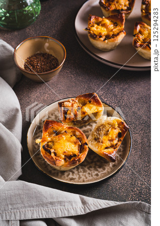Homemade caramelized onion savory pies on a plate on the table vertical view Homemade caramelized onion savory pies on a plate on the table vertical view 125294283