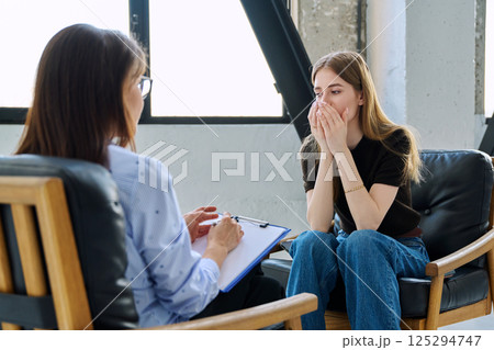 Sad upset young woman patient in therapy session in psychologist office 125294747