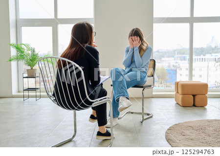 Sad unhappy patient young woman at mental session in office of professional mental therapist 125294763