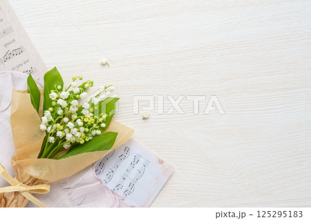 ナチュラルなスズランの花束と楽譜｜木目背景 125295183