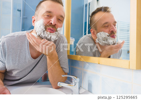 Guy shaving his beard in bathroom Guy shaving his beard in bathroom 125295665