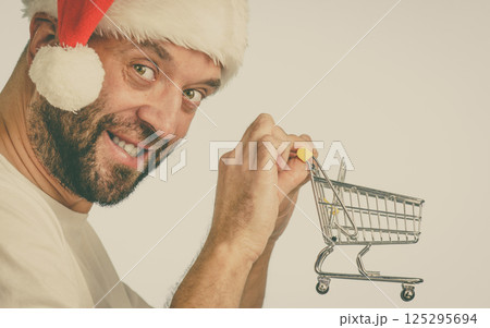 Santa man holding shopping cart Santa man holding shopping cart 125295694