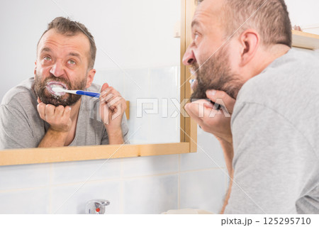 Bored guy brushing his teeth in bathroom Bored guy brushing his teeth in bathroom 125295710
