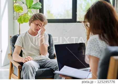 Sad teenage boy in mental therapy session, talking with behavioral psychologist Sad teenage boy in mental therapy session, talking with behavioral psychologist 125295776