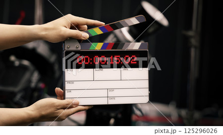 Digital film slate for filmmaker in set. Hand hitting timecode clapperboard or movie slate for Video Production. Digi number clapper board or film slates action on set. Tools in modern cinema industry 125296026
