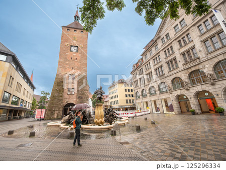 Nuremberg, Germany, August 2, 2023. Nuremberg, Germany, August 1, 2023. Nice shot of the White Tower or Weber Tower. A young man with an umbrella looks around, on a rainy day. 125296334