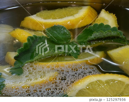 Homemade lemonade. Orange, lemon and mint pieces in a large container with spring water. Close-up Homemade lemonade. Orange, lemon and mint pieces in a large container with spring water. Close-up 125297936