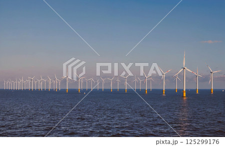 Long line of wind turbines are in the water. The wind turbines are in the water and are very tall 125299176