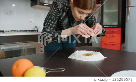 Woman Cracks Eggs For Homemade Easter Dessert Woman Cracks Eggs For Homemade Easter Dessert 125299575