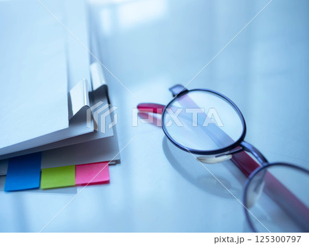 テーブルに置かれた書類とメガネ 125300797