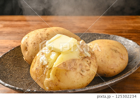 蒸したじゃがいもにバターをのせる 125302234