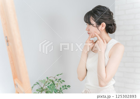 ニキビ・肌荒れ・吹き出物に悩む鏡を見るアジア人女性 ニキビ・肌荒れ・吹き出物に悩む鏡を見るアジア人女性 125302893