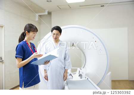 CTスキャンを受ける男性と放射線技師　撮影協力：学校法人電波学園　東京電子専門学校 125303392