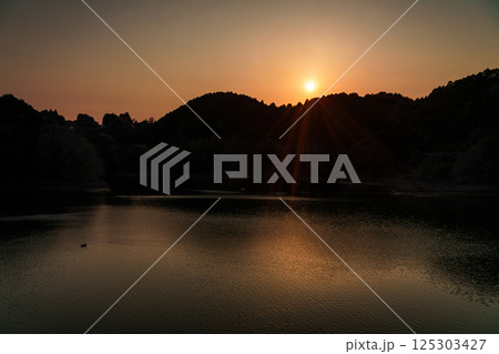 対岸の山並みに沈んで行く夕日　インターバル撮影連続写真　奈良布目ダムにて⑱ 125303427
