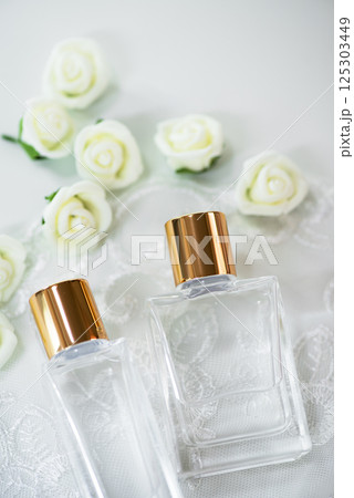 白いレースとバラとゴールドキャップのクリアガラス製コスメボトル 125303449