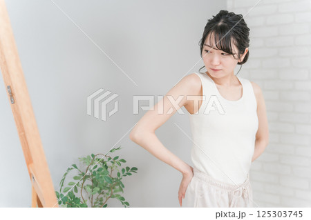 鏡でお尻をチェックして悩むアジア人女性（ヒップアップ） 125303745