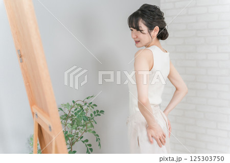 鏡でお尻をチェックして悩むアジア人女性（ヒップアップ） 125303750