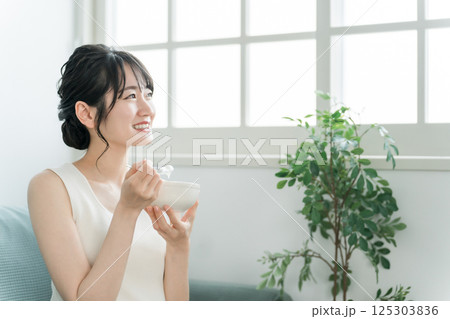 家のソファでヨーグルト・乳製品を食べるアジア人女性(ビフィズス菌・乳酸菌・乳製品・腸活) 家のソファでヨーグルト・乳製品を食べるアジア人女性(ビフィズス菌・乳酸菌・乳製品・腸活) 125303836