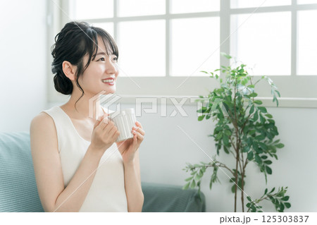 マグカップで朝、家でお茶・白湯を飲むリラックスするアジア人女性（温活） 125303837