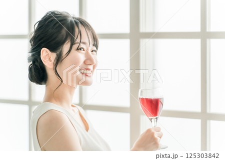 家で赤い飲み物を昼飲みするアジア人女性（赤ワイン・アセロラ・ザクロ・シソ・ポリフェノール・タンニン） 125303842