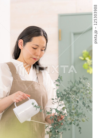 室内で植物の世話をする笑顔の大人女性｜健康的な暮らしイメージ｜ウェルビー女子｜ウェルビーイング 125303988