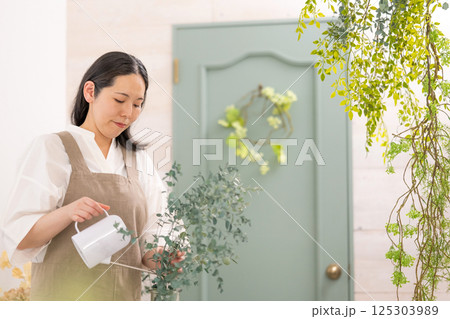 室内で植物の世話をする笑顔の大人女性｜健康的な暮らしイメージ｜ウェルビー女子｜ウェルビーイング 125303989