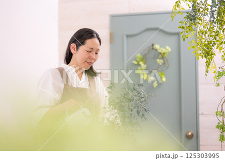 室内で植物の世話をする笑顔の大人女性｜健康的な暮らしイメージ｜ウェルビー女子｜ウェルビーイング 125303995