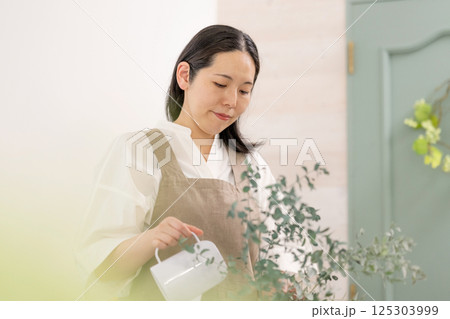 室内で植物の世話をする笑顔の大人女性｜健康的な暮らしイメージ｜ウェルビー女子｜ウェルビーイング 125303999
