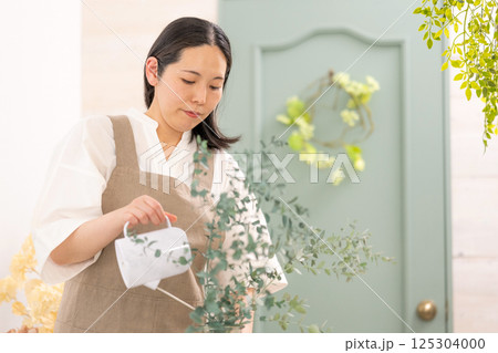 室内で植物の世話をする笑顔の大人女性｜健康的な暮らしイメージ｜ウェルビー女子｜ウェルビーイング 125304000