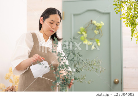 室内で植物の世話をする笑顔の大人女性｜健康的な暮らしイメージ｜ウェルビー女子｜ウェルビーイング 125304002