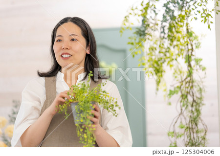 室内で植物の世話をする笑顔の大人女性|健康的な暮らしイメージ|ウェルビー女子|ウェルビーイング 室内で植物の世話をする笑顔の大人女性|健康的な暮らしイメージ|ウェルビー女子|ウェルビーイング 125304006