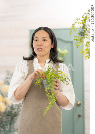 室内で植物の世話をする笑顔の大人女性｜健康的な暮らしイメージ｜ウェルビー女子｜ウェルビーイング 125304007
