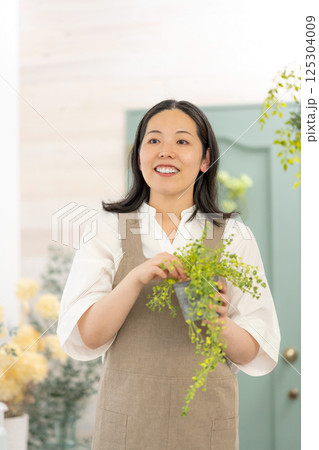 室内で植物の世話をする笑顔の大人女性｜健康的な暮らしイメージ｜ウェルビー女子｜ウェルビーイング 125304009