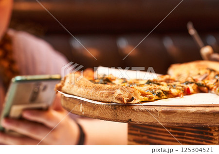 Close-up of pizza slices on a wooden stand in a cafe. Close-up of pizza slices on a wooden stand in a cafe. 125304521