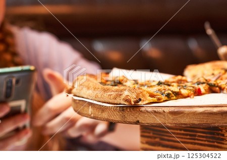 Close-up of pizza slices on a wooden stand in a cafe. 125304522