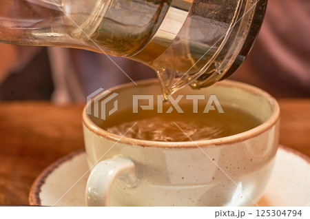 Tea is poured into a cup of green tea, close-up. Selective focus. Tea is poured into a cup of green tea, close-up. Selective focus. 125304794
