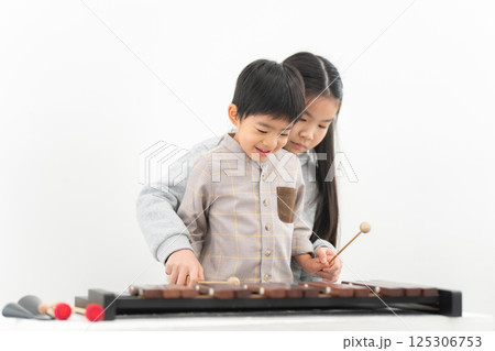弟に木琴を教える姉 125306753