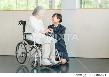 介護施設を訪れた孫娘と車椅子の祖母（お見舞い・老人ホーム・介護・入院・病院） 125306871