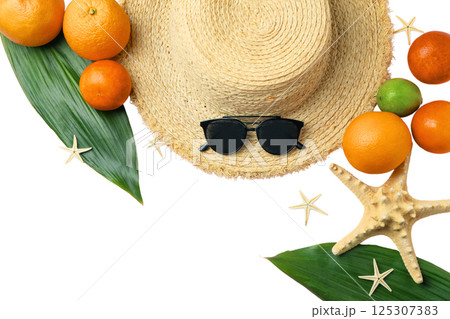 A straw hat surrounded by vibrant fruits on green leaves, isolated on white background 125307383