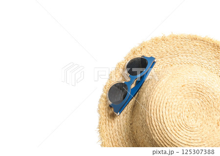 Straw hat with sunglasses laid next to it, perfect for summer travel, isolated on white 125307388