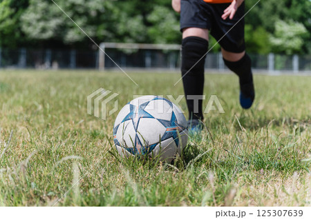 Close-up of young football player kicking soccer ball. 125307639