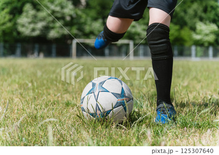 Close-up of young football player kicking soccer ball. 125307640