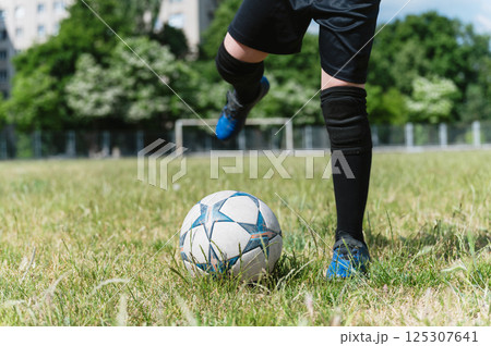Close-up of young football player kicking soccer ball. 125307641