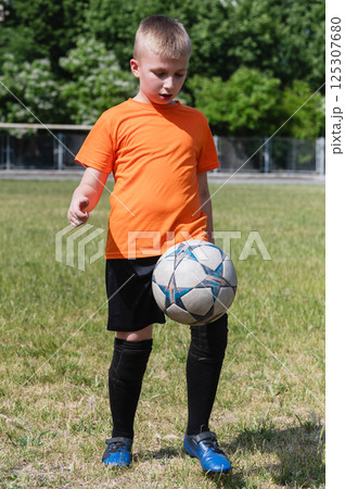 Boy juggling soccer ball on grassy field in sunlight. Boy juggling soccer ball on grassy field in sunlight. 125307680