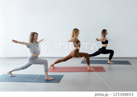 Young girls in a warrior pose at a group yoga class. Healthy lifestyle and female beauty 125308653