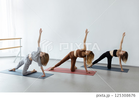 A group of girls practice yoga asanas in the studio.Group yoga classes with an instructor A group of girls practice yoga asanas in the studio.Group yoga classes with an instructor 125308676